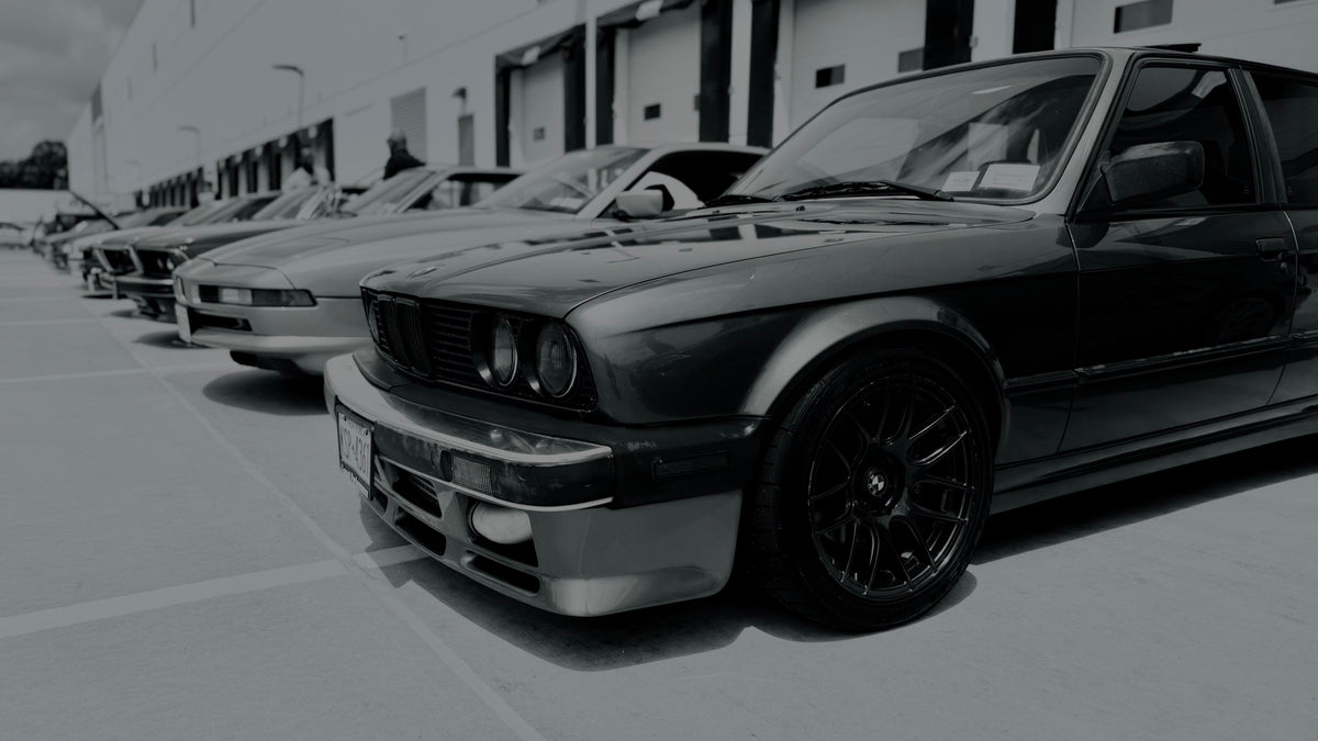 BMW E30 and other cars lined up at a meet